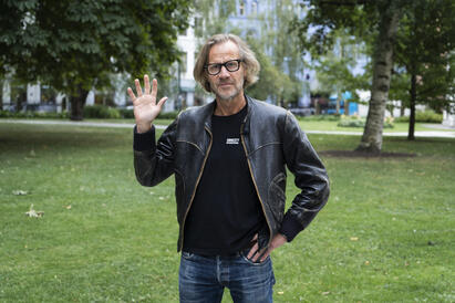 Bilde viser en mann som ser i kamera og  holder opp h&aring;nden