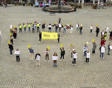 To personer holder opp en Amnetsy-banner, mens en gruppe mennesker st&aring;r i ring rundt dem