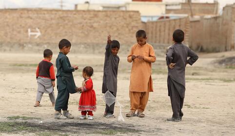 Barn st&aring;r ved siden av hverandre ute.