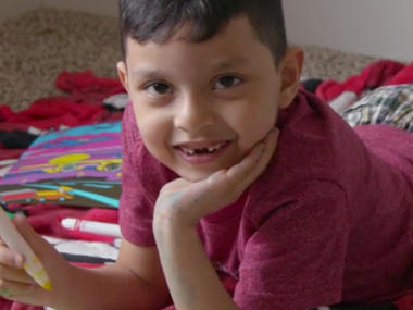 Carlos fra Mellom-Amerika ligger p&aring; gulvet og smiler til kameraet. 