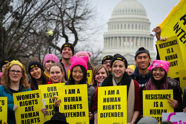 Amnesty-aktivister og st&oslash;ttespillere med plakater "I am a human rights defender". 