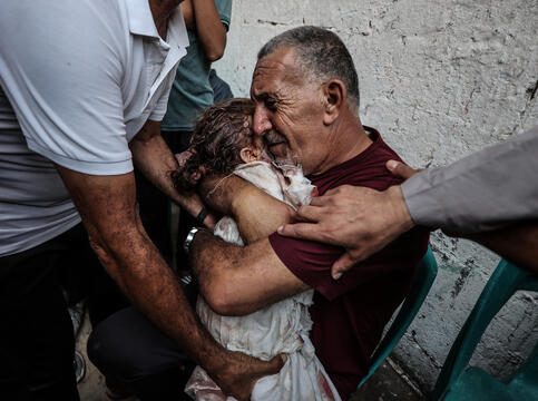 Mann klemmer en liten jente. Personer st&aring;r rundt og st&oslash;tter dem med hendene
