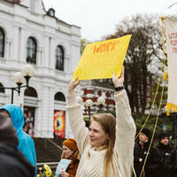 Aktivist med gul plakat under demonstrasjon for menneskerettigheter