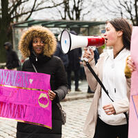 To unge jenter demonstrerer for menneskerettigheter, en holder plakat og en bruker ropert